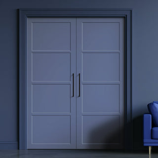 Image: A pair of primed blue internal wooden doors with a panel design, situated in a darker blue or grey room, with a modern handle on each door and a visible sample chair to the side.