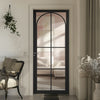 A black internal door with clear glass panes, prefinished, installed in an interior setting with a visible architrave.