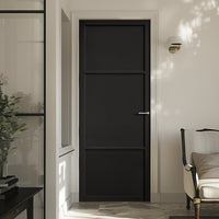 A prefinished black internal door with three panels, installed in an interior setting with light walls and a visible light fixture above the door.