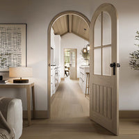 A Prefinished Mexicano Arched Blonde Oak Internal Door & Frame Set with clear bevelled glass installed in a room, showcasing a modern yet traditional design.