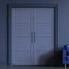 A pair of primed blue internal wooden doors with a panel design, situated in a darker blue or grey room, with a modern handle on each door and a visible sample chair to the side.